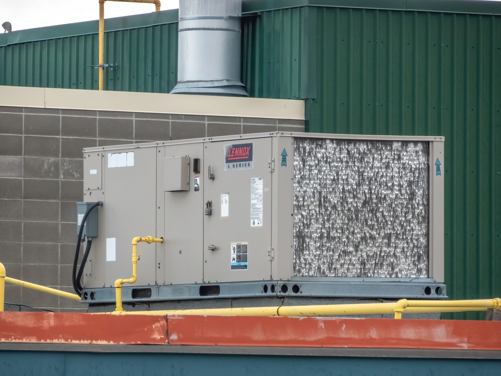 Technician applying a high-grade foaming chemical cleaner to a commercial RTU condenser coil, showing white foam lifting deep-seated debris out of the aluminum fins.