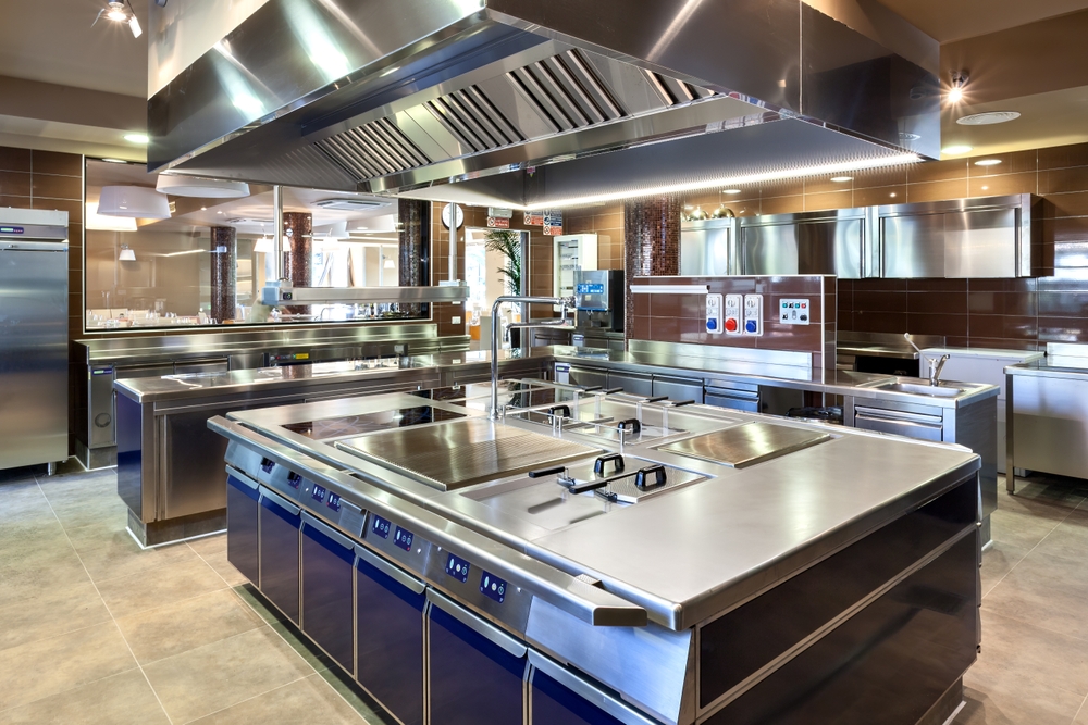 Stainless steel Type 1 commercial kitchen exhaust hood with integrated make-up air plenum installed above a cookline in a Baytown restaurant.