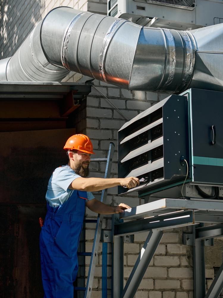 Welder working under a high-velocity Source Capture Local Exhaust Ventilation (LEV) arm to remove fumes and lower the ambient heat load in a Baytown industrial facility.